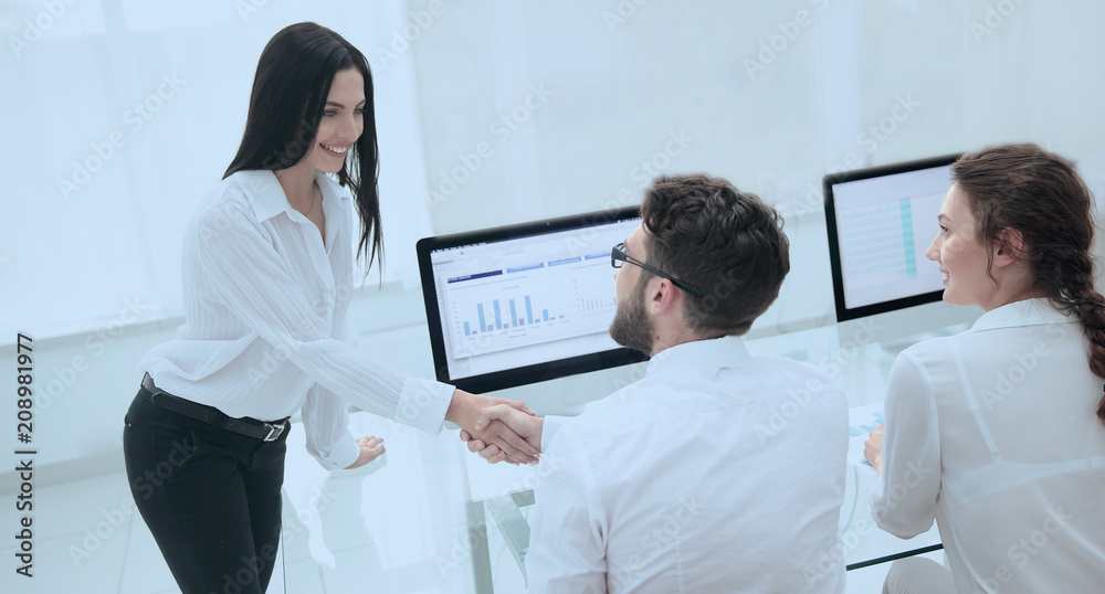 employees greet each other with a handshake near the desk employees greet each other with a handshake near the desk
