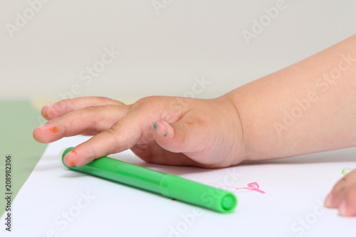 close up on the hand of a child who draws with colored markers
