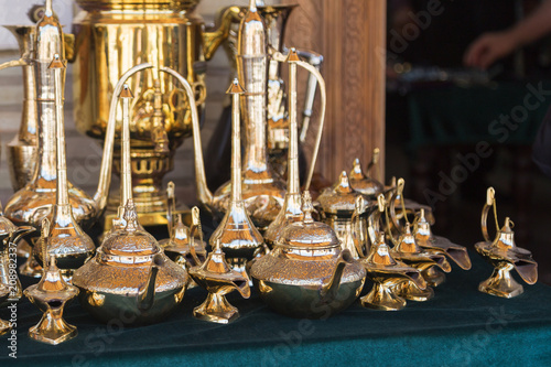 A magical lamp of aladdin, Gold handmade kettles exhibited for sale. Souvenirs shop with golden different size teakettles. Trading with bronze pots. photo