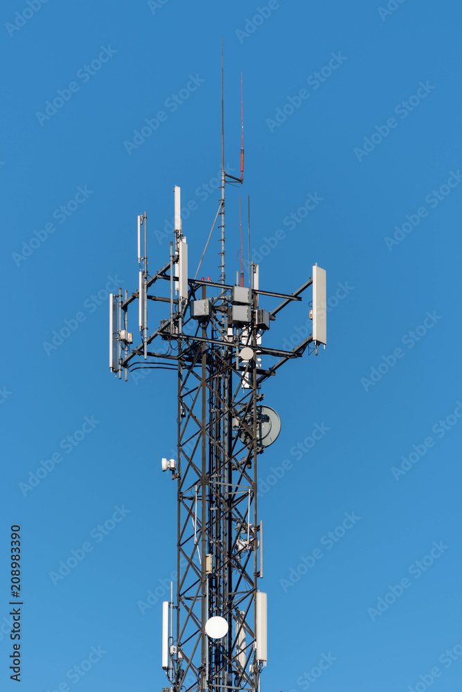 Top of communication tower on a blue background, vertical photo.
