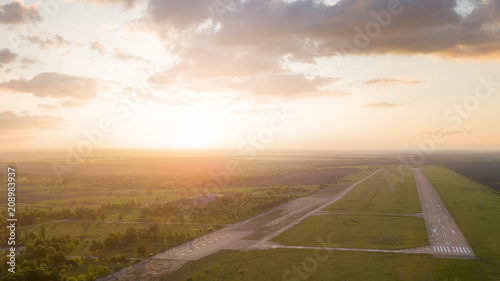 Aerial view from the drone, a bird's eye view of abstract geometric forms of abandoned runway, forests and fields in the summer evening at sunset.