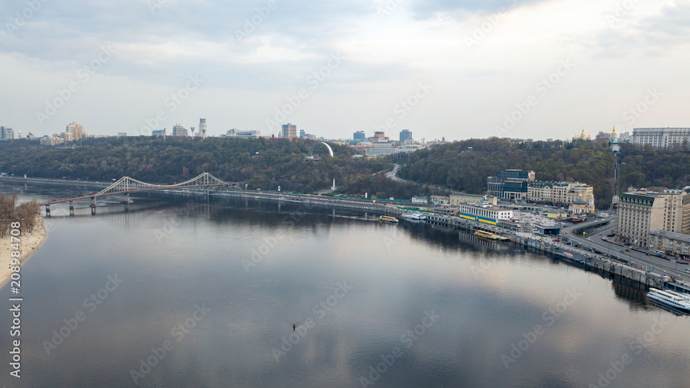 The panoramic bird's eye view shooting from drone of the Podol district, the right bank of the Dnieper River and centre of Kiev, Ukraine summer evening at sunset on the background of the cloudy sky.