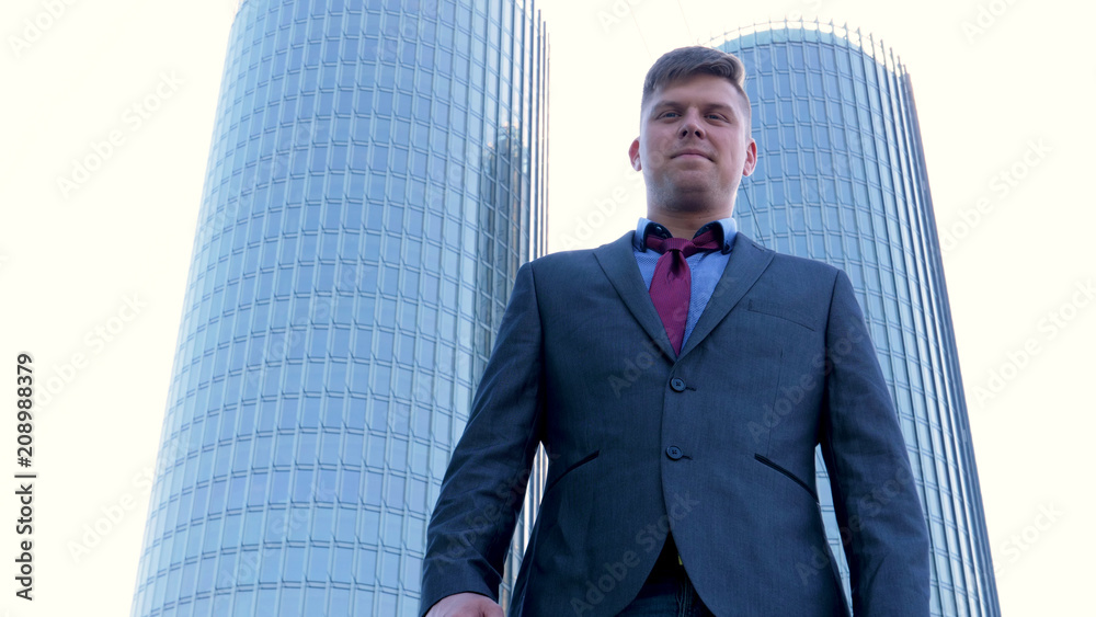 Fototapeta premium Young handsome businessman in suit, skyscraper background