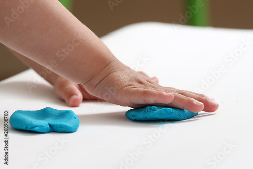 close-up of a child's hand playing with blue and violet modeling clay