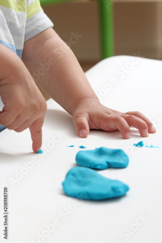 close-up of a child's hand playing with blue and violet modeling clay