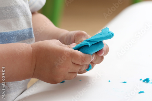 close-up of a child's hand playing with blue and violet modeling clay