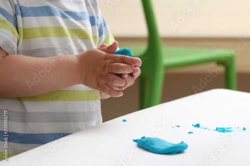 close-up of a child's hand playing with blue and violet modeling clay