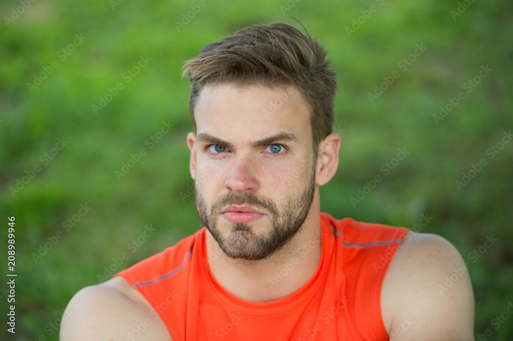 Taking minute break. Runner relaxing in shadow. Man with bristle strict face, grass background. Man unshaven looks handsome and cool. Guy bearded and attractive relaxing at meadow during workout Taking minute break. Runner relaxing in shadow. Man with bristle strict face, grass background. Man unshaven looks handsome and cool. Guy bearded and attractive relaxing at meadow during workout