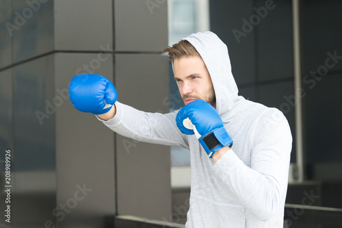 Canvas Print Man athlete on concentrated face with sport gloves practicing boxing punch, urban background