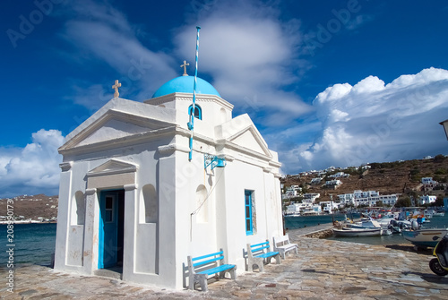 Agios Nikolaos church in Mykonos, Greece. Temple building with blue dome on sea quay. Church on sunny seaside. Summer vacation on mediterranean island. Wanderlust and travelling concept