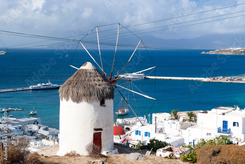 Windmill on seascape in Mykonos, Greece. Windmill on mountain by sea on sky. Whitewashed building with sail and straw roof with nice architecture. Summer vacation on island. Landmark and attraction