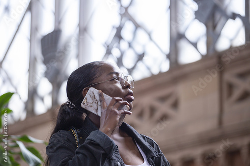 Young black woman at train station with a smartphone