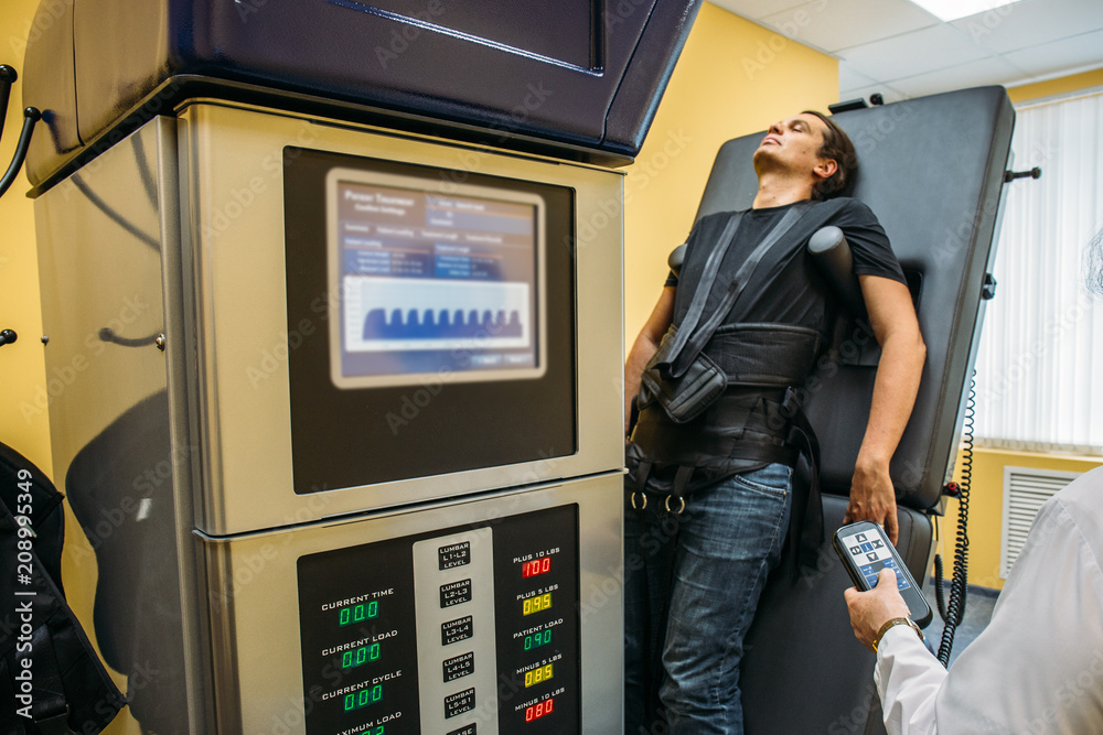 Male patient at non-surgical treatment physiotherapy of lumbar spine and spinal cord dilatation in medical center on special medical equipment Male patient at non-surgical treatment physiotherapy of lumbar spine and spinal cord dilatation in medical center on special medical equipment