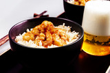 Fried shrimp and rice in a black bowl. Glass with beer. The background is gray. Tonad.