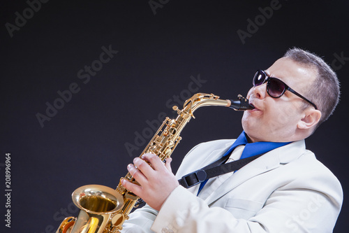 Music Themes and Ideas. Passionate Caucasian Mature Saxophonist Against Black Background.