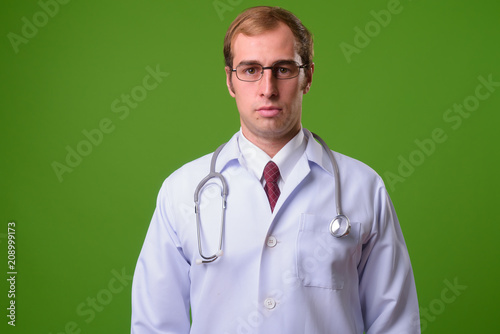 Young man doctor against green background