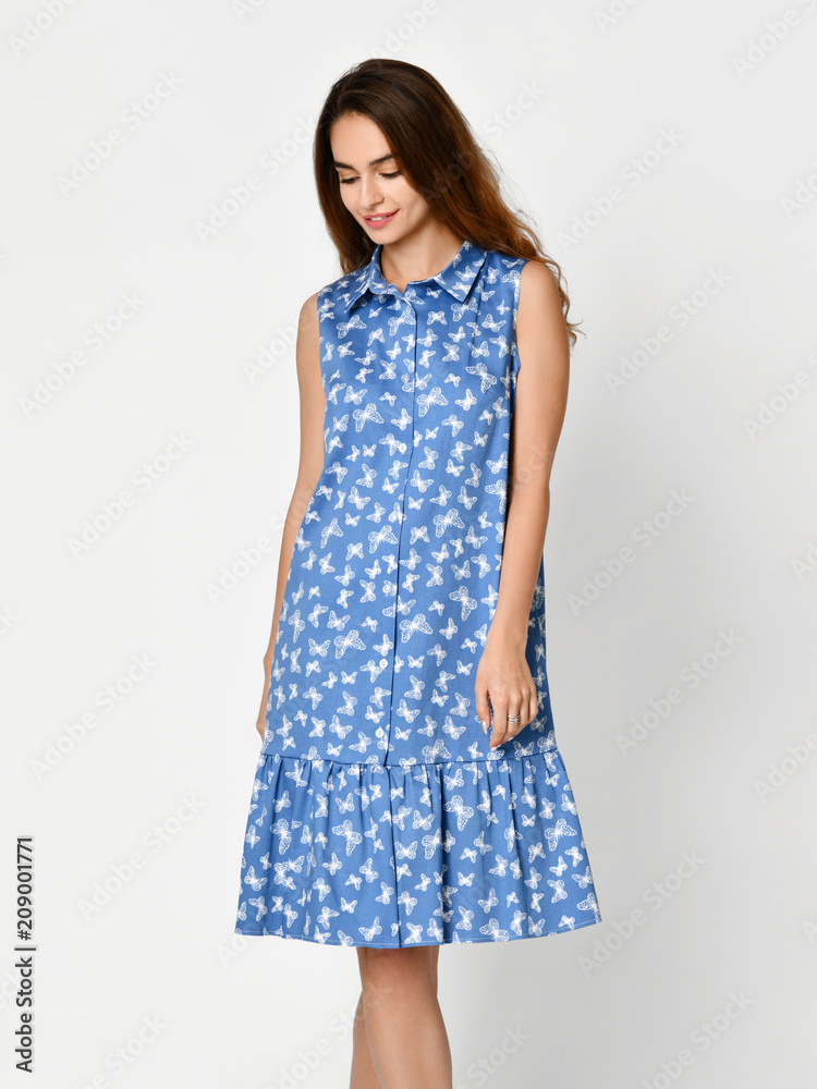 Young beautiful woman posing in new blue stripes casual summer dress on grey Young beautiful woman posing in new blue stripes casual summer dress on grey