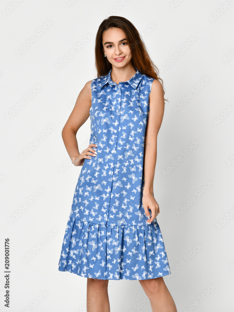 Young beautiful woman posing in new blue stripes casual summer dress on grey Young beautiful woman posing in new blue stripes casual summer dress on grey