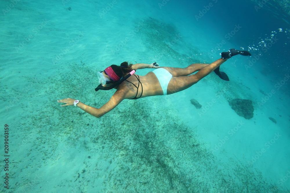 Female free diver snorkeling in bikini in clear tropical water