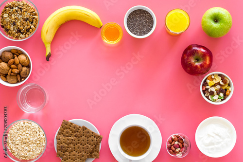 Ideas of healthy hearty breakfast for sportsmen. Fruits, oatmeal, yogurt, nuts, crispbreads, chia on pink background top view copy space