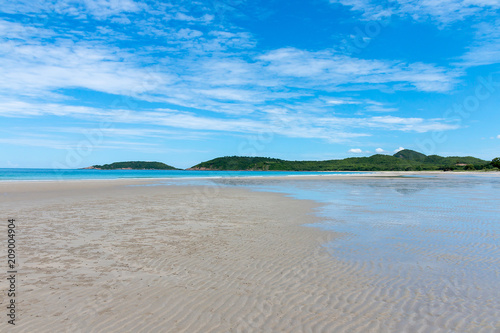 Fototapeta Naklejka Na Ścianę i Meble -  Golden sand beach, Beautiful white clouds on blue sky over calm sea with sunlight reflection and the island is full of trees.