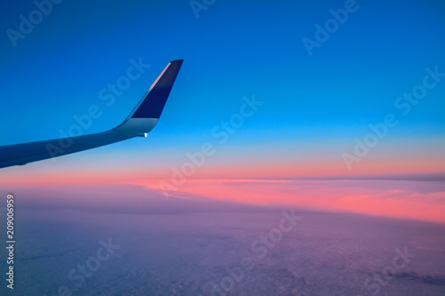 Landscape sunrise over the clouds seen from the window of a flying passenger airliner. View of the wing aircraft. Air travel. © Konstantin