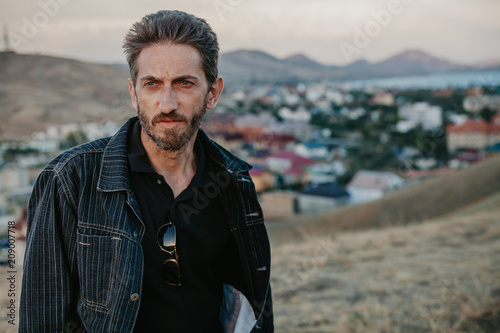 young man with beard against backdrop of mountains