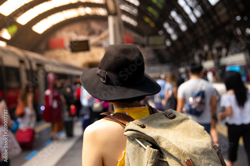 Young backpacker hipster woman waiting for the train at platform in train station.