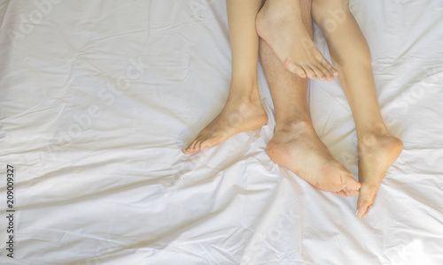 Feet of couple side by side in bed. Up view