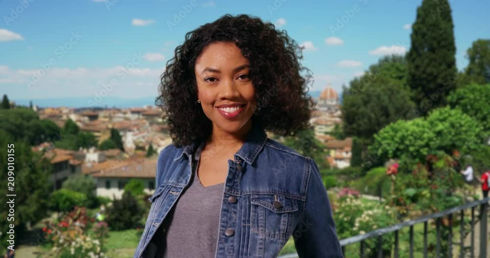 Happy African American woman in denim jacket laughing on vacation in Florence, Beautiful black woman tourist in jean coat smiling at camera on trip to Italy, 4k Happy African American woman in denim jacket laughing on vacation in Florence, Beautiful black woman tourist in jean coat smiling at camera on trip to Italy, 4k