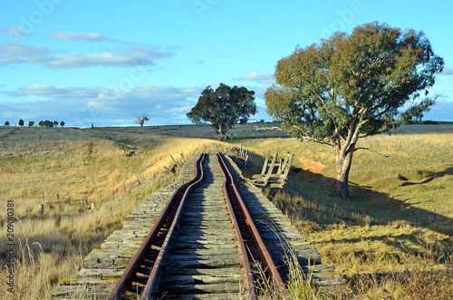 Old abandoned crooked rusty railway tracks on historic bridge over the Boorowa River through rural central west NSW, Australia