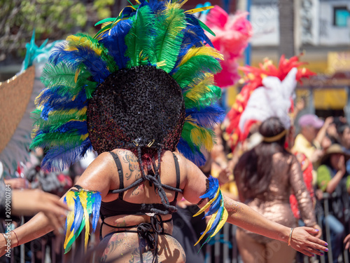 Woman wearing Aztec feather head wear, marching down a parade
