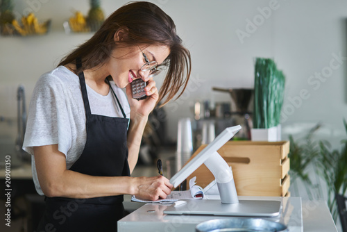 shop assistant taking order on phone in restaurant photo