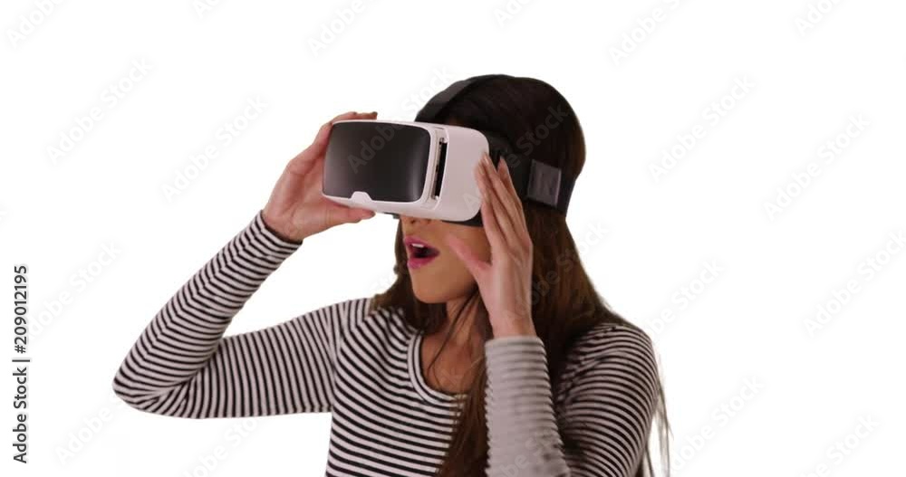 Cute Latina woman using vr headset on white background, amazed by what she sees, Portrait of excited woman using virtual reality goggles in studio, 4k Cute Latina woman using vr headset on white background, amazed by what she sees, Portrait of excited woman using virtual reality goggles in studio, 4k