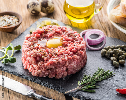 Steak tartare served with raw quail egg yolk and other tartare ingredient. Meat dish.