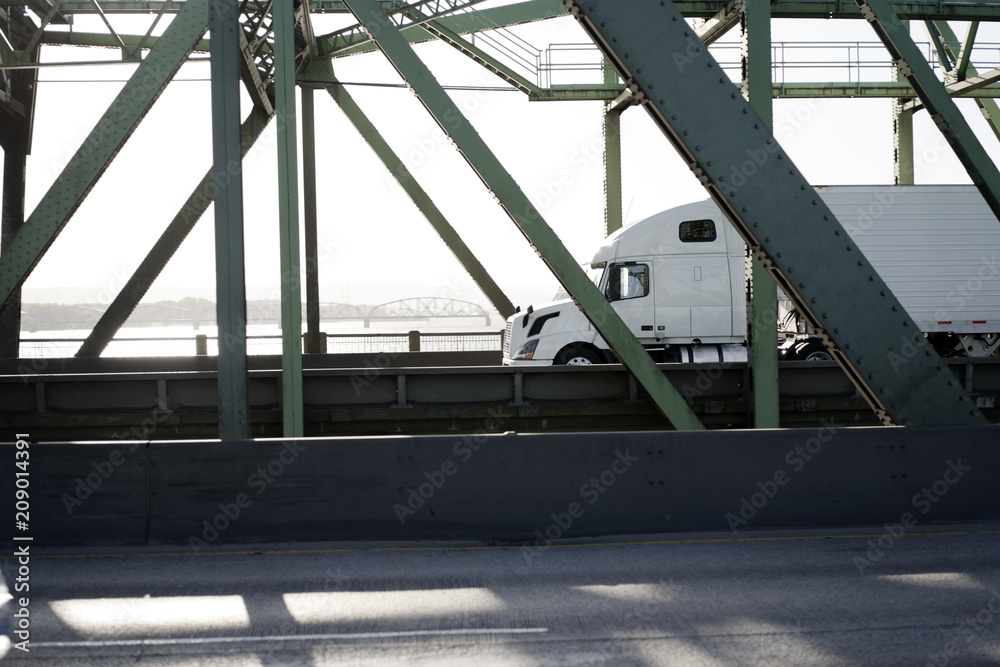 Big rig long haul semi truck running on the bridge in sunshine Big rig long haul semi truck running on the bridge in sunshine