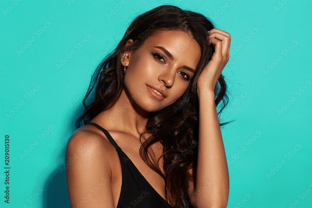 Young Sexy Slim Tanned Woman In Black Swimsuit Posing Against Blue Young Sexy Slim Tanned Woman In Black Swimsuit Posing Against Blue