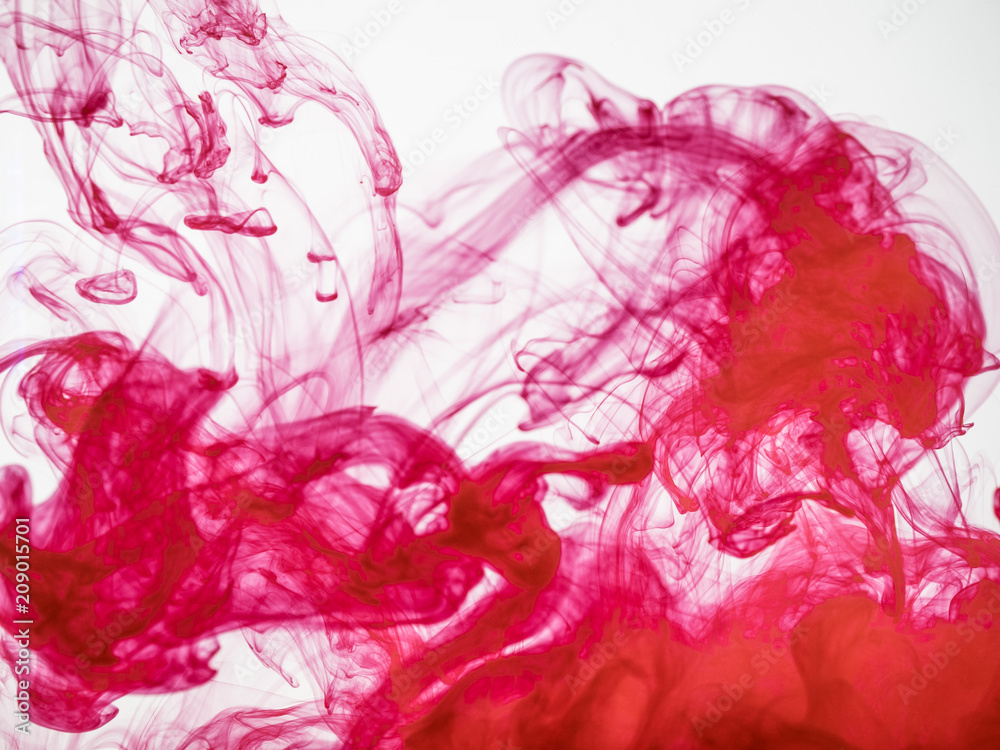 Process of dissolving acrylic ink into water. Amazing abstract background. Splash of colourful paint photographed while in motion. Acrylic cloud in liquid. Droplet of red color dissipation in liquid