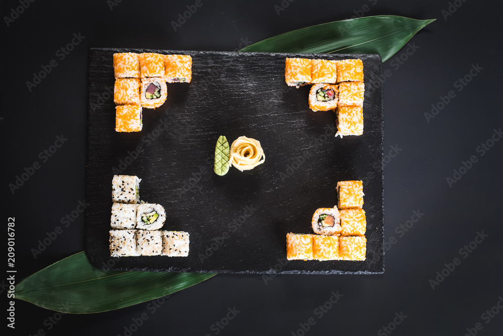 Obraz premium A set of different sushi rolls with caviar on black background
