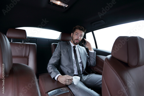 businessman sitting in car with cup and smartphone © ASDF