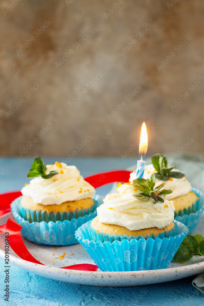 Birthday cupcake with whipped cream, poppy and orange peel on a blue a stone or slate background. Copy space. Birthday cupcake with whipped cream, poppy and orange peel on a blue a stone or slate background. Copy space.