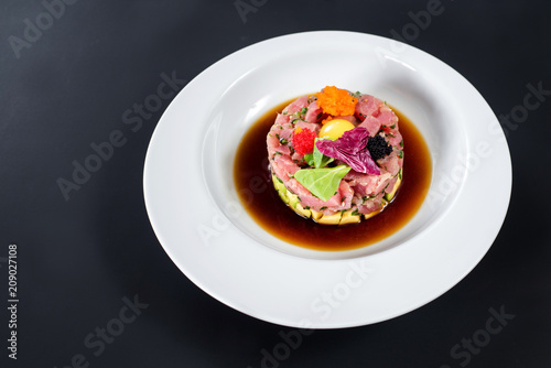 Tasty tartar salad on black background