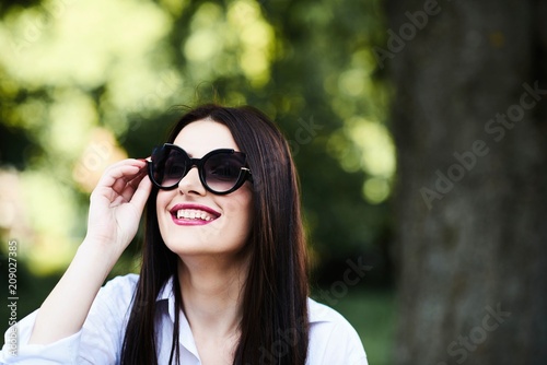 Cute young brunette girl with beautiful professional make-up sitting in a street cafe on a beautiful sunny day