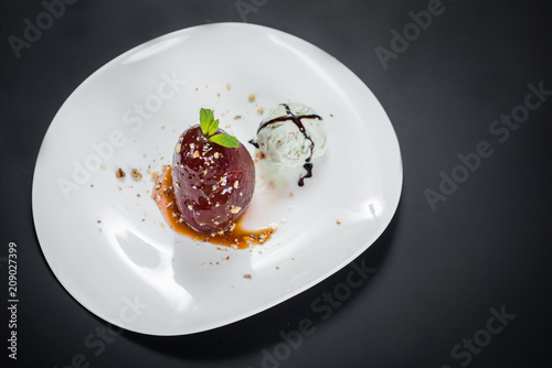 A dessert with caramelized pear and ice on black background