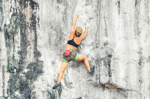 Young blonde woman climbing a cliff without insurance