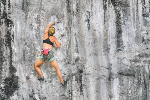 Young woman climbing a cliff without safety equipment on a summer day  copy space