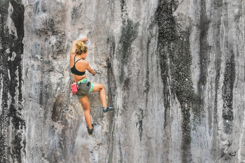 Young woman climbing a cliff without insurance, copy space