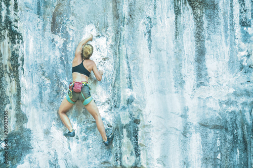 Young woman climbing a cliff without insurance. Toned