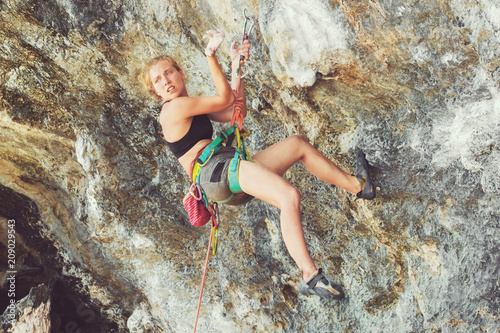 Young blonde woman with a safety rope on a cliff