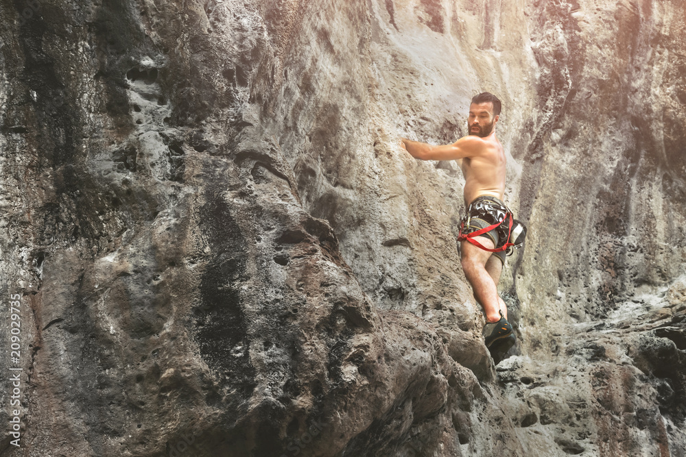 Young male mountain climber on a cliff, copy space